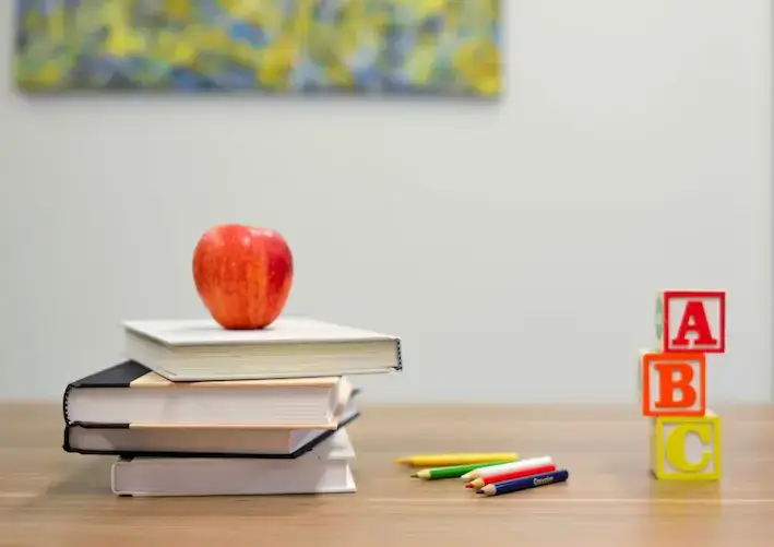 Red apple on top of a pile of four books