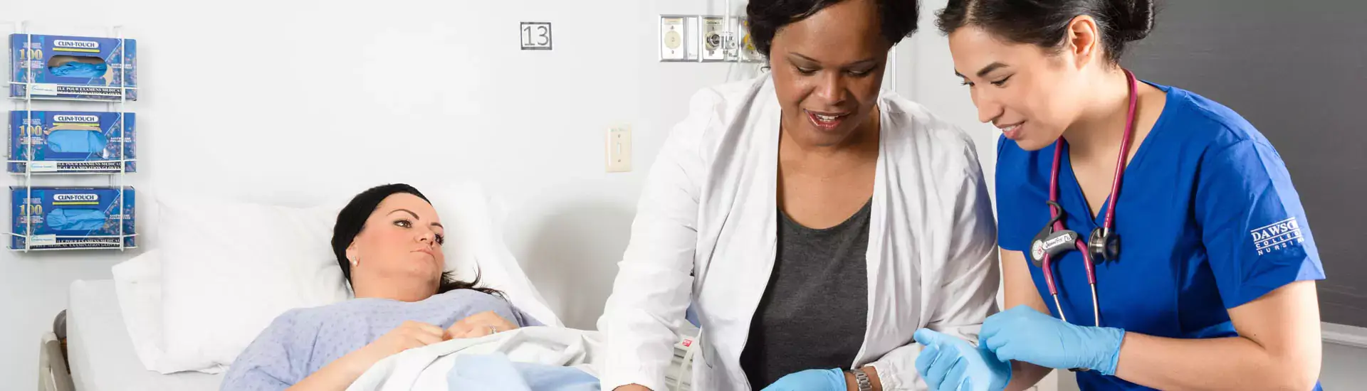 A health instructor and nursing student by a patient's bedside