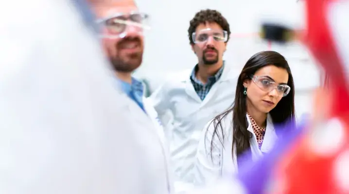 Students in lab coats and safety glasses in a science lab