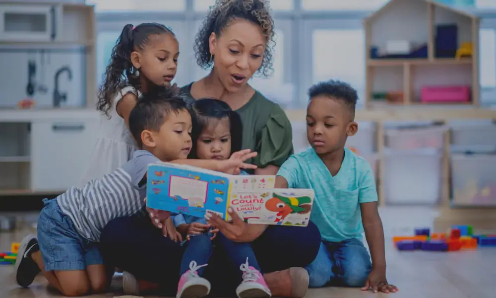 An adult reading a children's book to some young kids